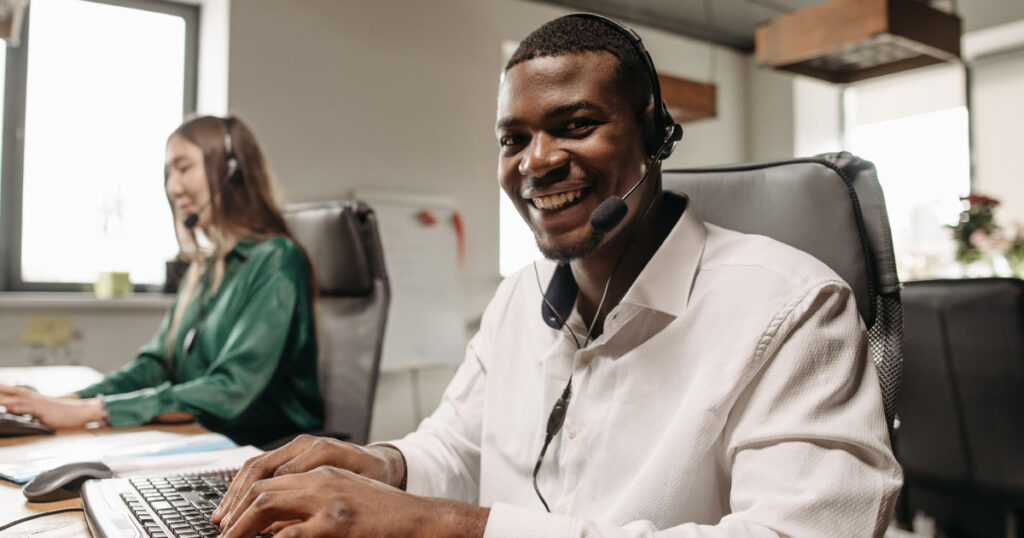 Profissionais de vendas com headset realizando prospecção de clientes por telefone em ambiente de atendimento corporativo.