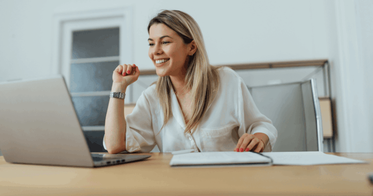 Mulher sorrindo enquanto analisa informações no notebook em um escritório, representando um momento de tomada de decisão nas empresas