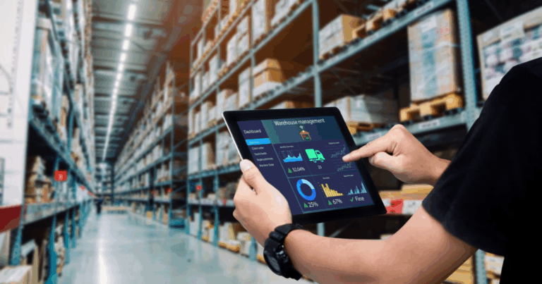 Pessoa utilizando um tablet para monitorar dados de gestão logística, com gráficos e informações de armazém, em um ambiente de estoque.