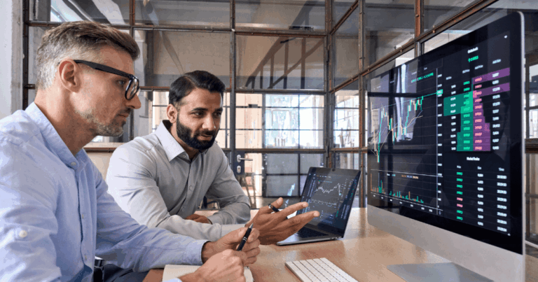 Profissionais analisando gráficos e indicadores em tela de computador para identificar tendências do mercado e oportunidades de investimento.