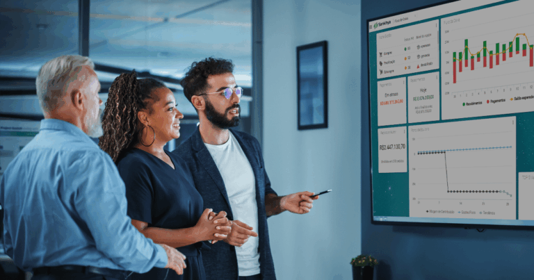 Pessoas ao redor de uma televisão com a visão dos cards interativos do ERP Sankhya, aliado na gestão comercial.