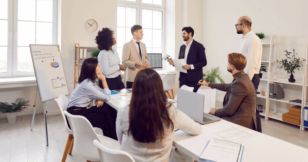 Equipe de profissionais em reunião corporativa discutindo relatórios e gráficos, representando o conceito de gestão de ativos dentro de uma empresa.