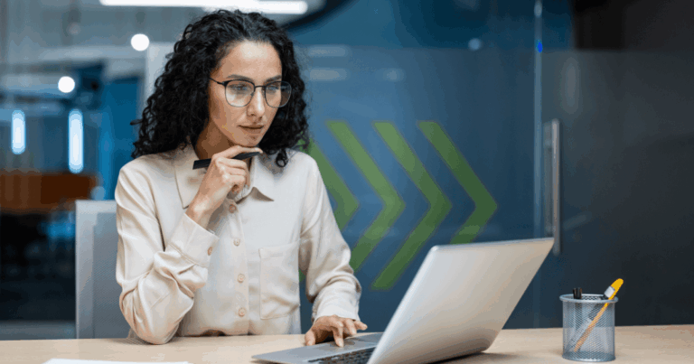 Mulher de óculos trabalhando concentrada em um laptop em ambiente corporativo moderno, simbolizando a análise e gestão estratégica relacionadas à governança corporativa.