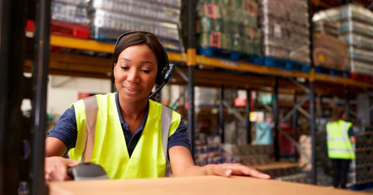 Funcionária realizando a reposição de estoque em um armazém, com foco na organização e eficiência do processo logístico.