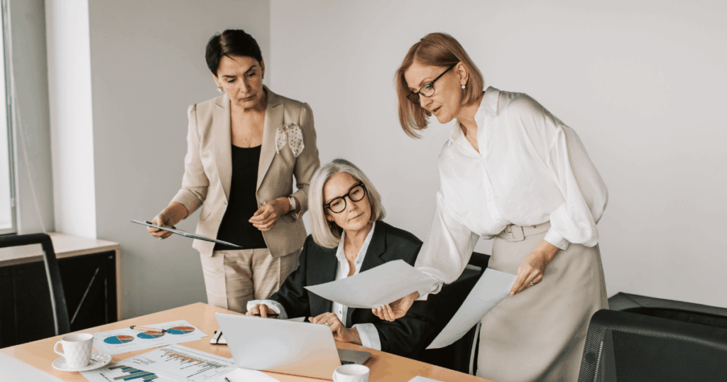 Mulheres executivas em reunião analisando relatórios e discutindo melhorias na cultura organizacional.