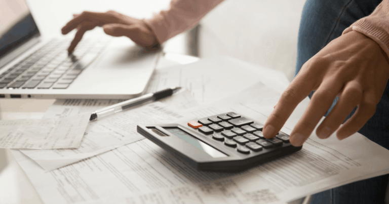 mãos de uma pessoa fazendo cálculos na calculadora com vários papéis representando os tipos de notas fiscais