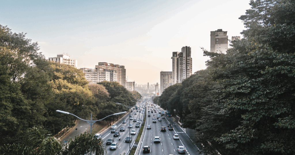 Avenida movimentada em uma grande cidade, com fluxo intenso de veículos e infraestrutura urbana integrada, representando os desafios e soluções da mobilidade urbana.