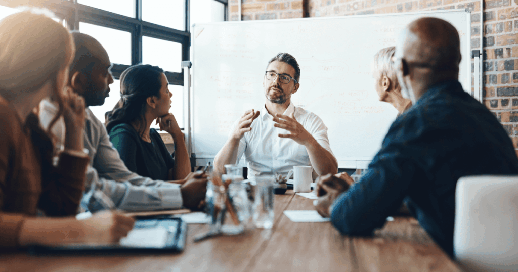 6 pessoas em uma sala de reunião falando sobre a importância da educação financeira nas empresas