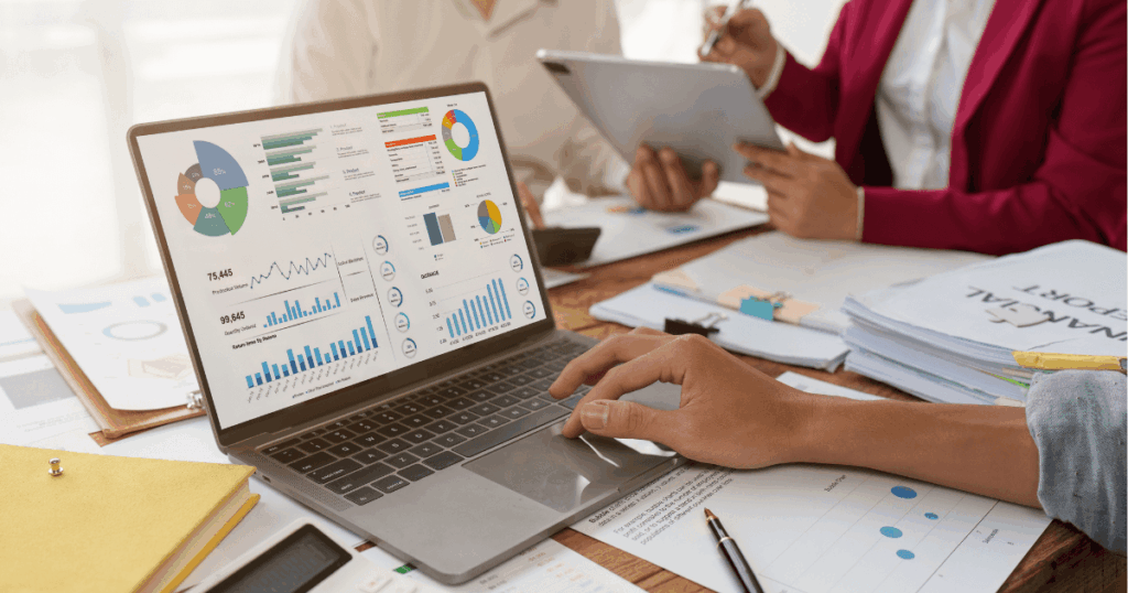 Equipe analisando relatórios financeiros e gráficos de desempenho no computador, com foco no cálculo e interpretação do EBITDA em ambiente corporativo.