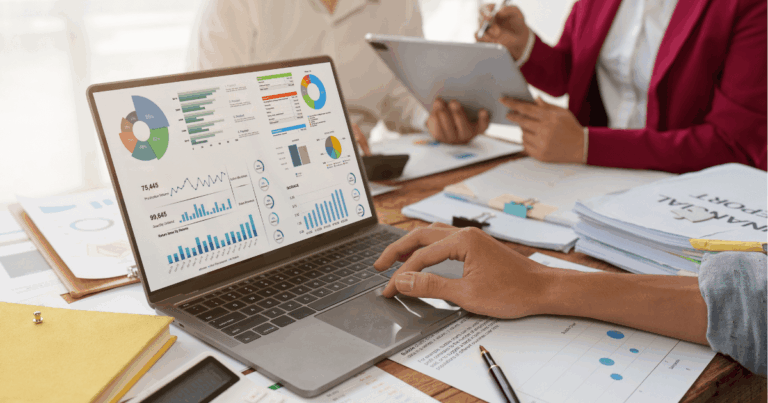 Equipe analisando relatórios financeiros e gráficos de desempenho no computador, com foco no cálculo e interpretação do EBITDA em ambiente corporativo.