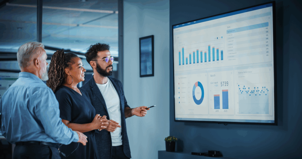 Equipe de profissionais analisando gráficos de desempenho e indicadores em uma tela, representando a aplicação prática de people analytics na gestão estratégica de pessoas.