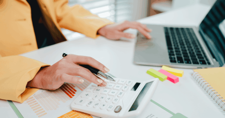 Profissional analisando documentos em frente ao notebook, representando o processo de apuração de custos nas empresas.