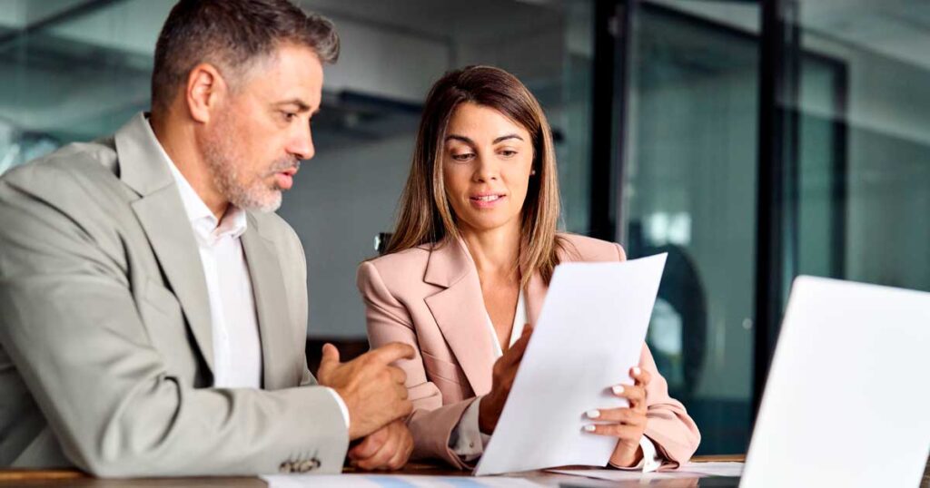 Profissionais analisando documentos em ambiente corporativo, representando a revisão de informações trabalhistas e cálculo do INSS para folha de pagamento e obrigações previdenciárias.