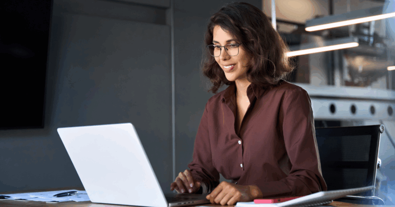 Profissional sorrindo ao utilizar sistema de folha de pagamento online em laptop no ambiente corporativo.