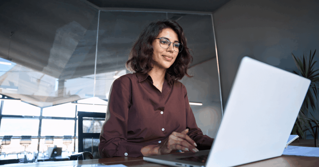 Profissional analisando dados no laptop em um escritório moderno, representando atividades de planejamento tributário.