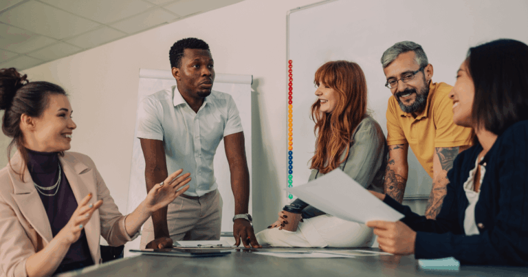 Equipe diversa engajada em uma dinâmica de team building, trocando ideias com descontração e colaboração em ambiente corporativo.