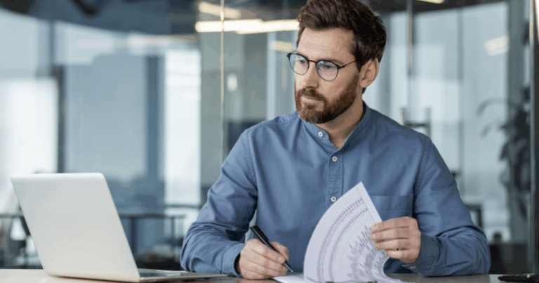 Profissional analisando documentos fiscais e tributários em frente ao computador, representando o cumprimento das obrigações acessórias no ambiente corporativo.