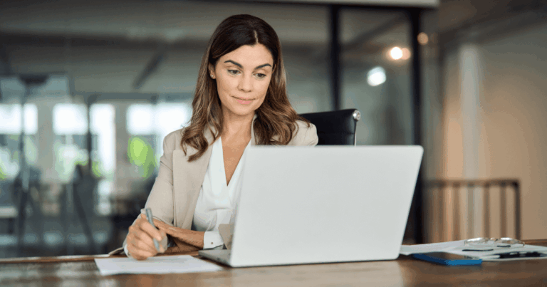 Executiva analisando relatórios financeiros no notebook, representando o uso estratégico da antecipação de recebíveis para melhorar o fluxo de caixa empresarial.