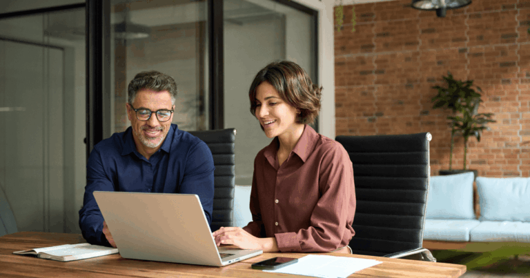 Profissionais analisando dados no notebook durante reunião estratégica, representando decisões sobre aportes financeiros em empresas de crescimento.