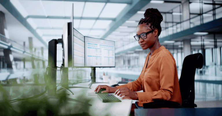 profissional trabalhando com múltiplas telas em ambiente corporativo moderno, utilizando sistemas de automação fiscal para controle e análise de dados tributários.