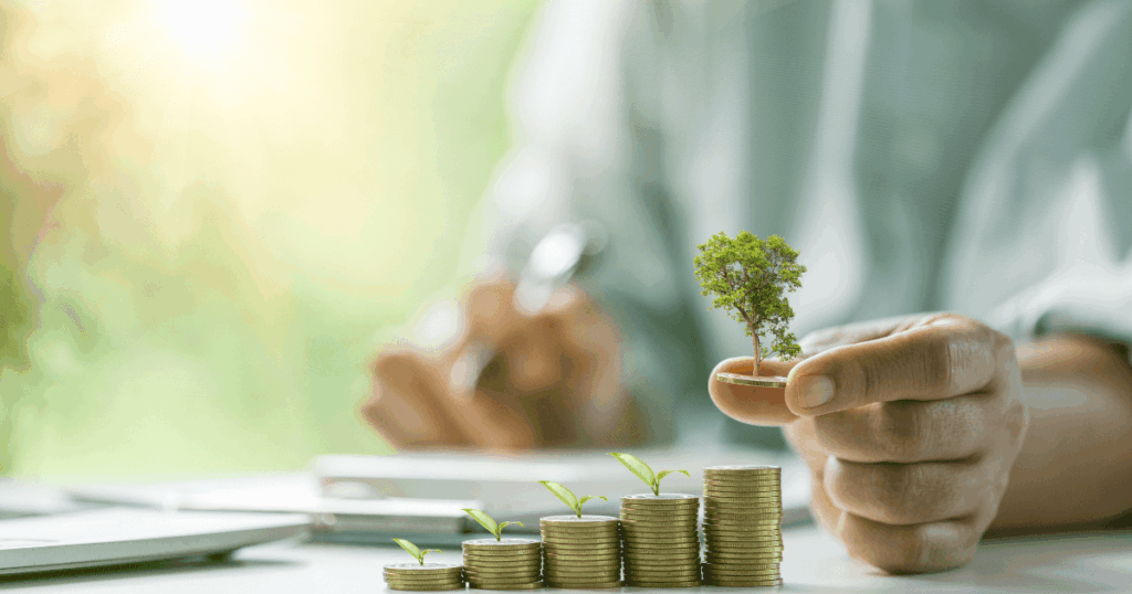 Pilha de moedas com brotos e árvore crescendo, simbolizando investimentos sustentáveis e os princípios da economia regenerativa voltados ao crescimento com impacto positivo.