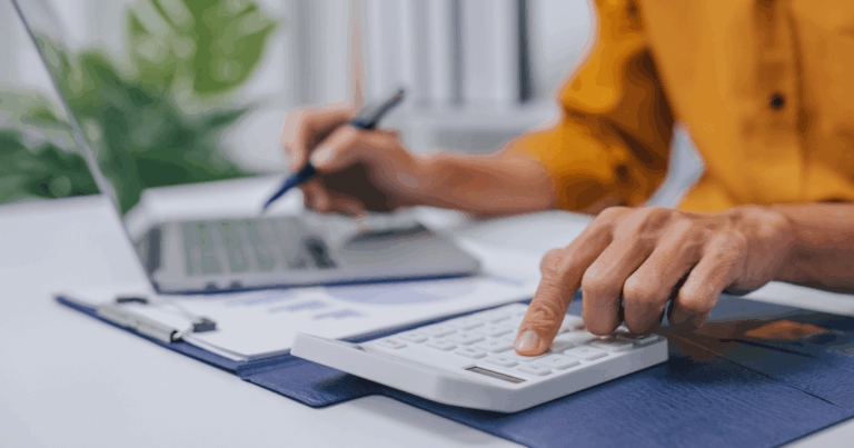 Pessoa calculando impostos no escritório com calculadora e notebook, ilustrando análise detalhada do IVA (Imposto sobre Valor Agregado) nas finanças empresariais.