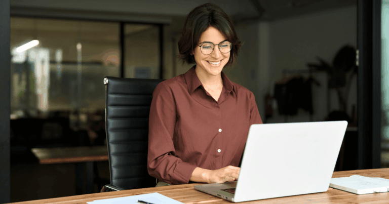 Colaboradora acessando conteúdo digital pelo notebook em ambiente empresarial, representando o uso da intranet corporativa para comunicação e produtividade interna.