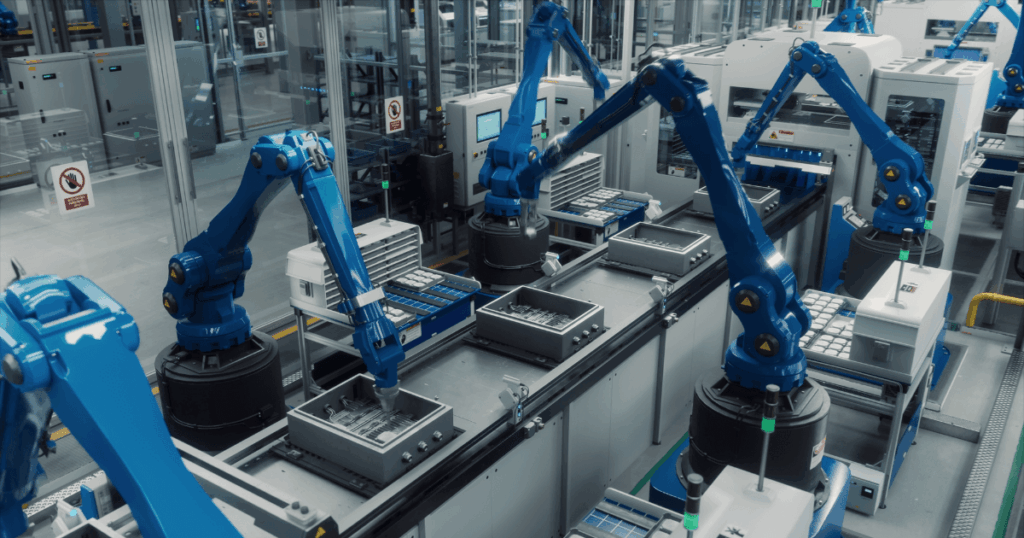 A imagem mostra uma linha de produção automatizada com robôs industriais azuis movimentando peças ao longo de uma esteira. O conceito de takt time é destacado, pois define o tempo necessário para produzir uma unidade de produto, ajudando a coordenar a velocidade de produção com a demanda, garantindo eficiência e evitando desperdícios.