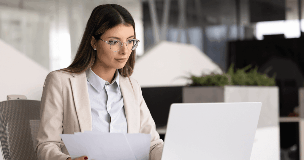 Profissional em escritório analisando documentos no computador, relacionada à gestão de obrigações tributárias e rotinas fiscais.