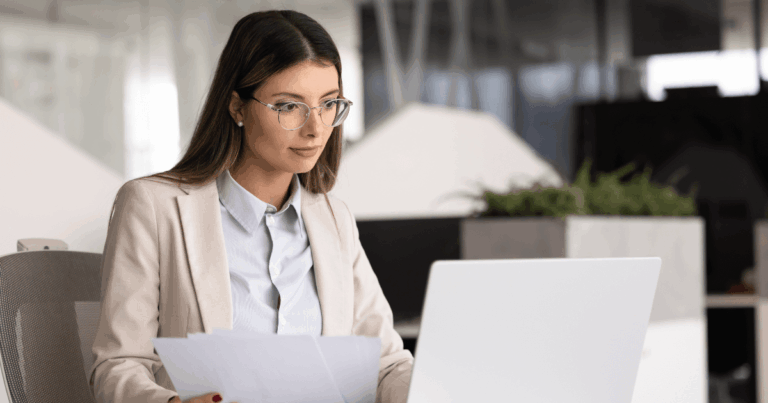 Profissional em escritório analisando documentos no computador, relacionada à gestão de obrigações tributárias e rotinas fiscais.