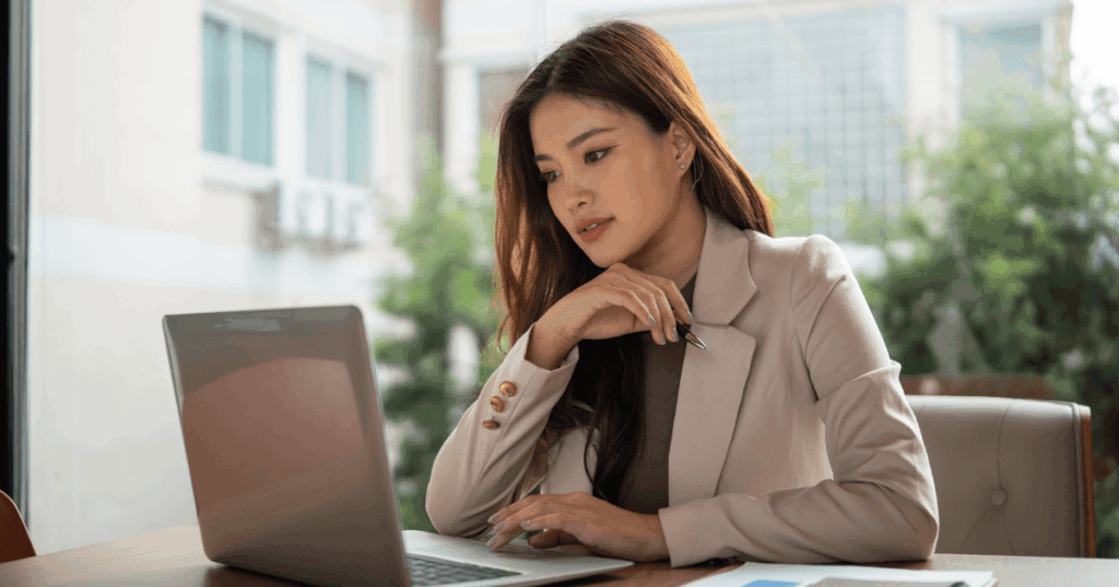 Mulher profissional analisando dados em um laptop em ambiente de escritório, representando estudo ou tomada de decisão financeira relacionada a spread cambial