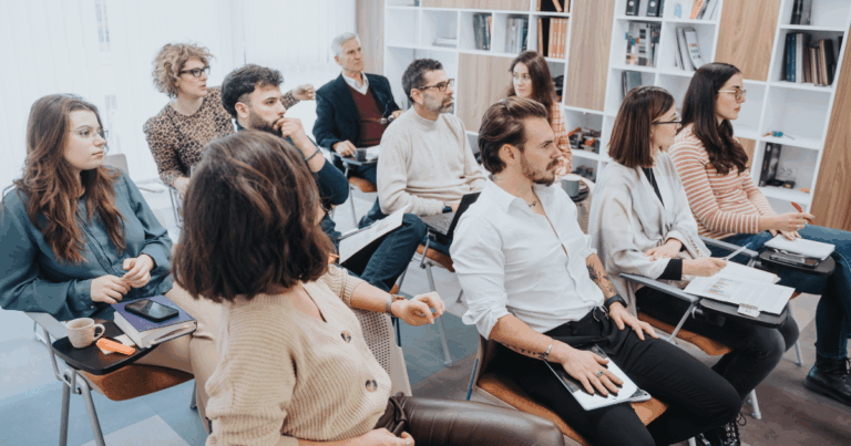 Colaboradores em treinamento empresarial com materiais e dispositivos digitais, representando a aprendizagem contínua nas empresas apoiada por tecnologia e plataformas LMS