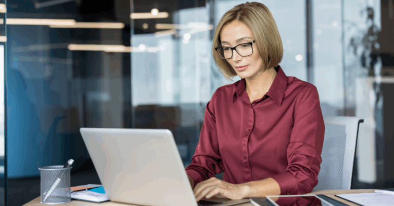 Profissional trabalhando em laptop em escritório moderno, realizando lançamentos contábeis e análise financeira com foco em organização e produtividade empresarial.